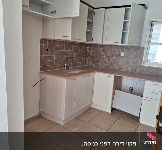 מטבח ריק עם ארונות פתוחים וברז כיור